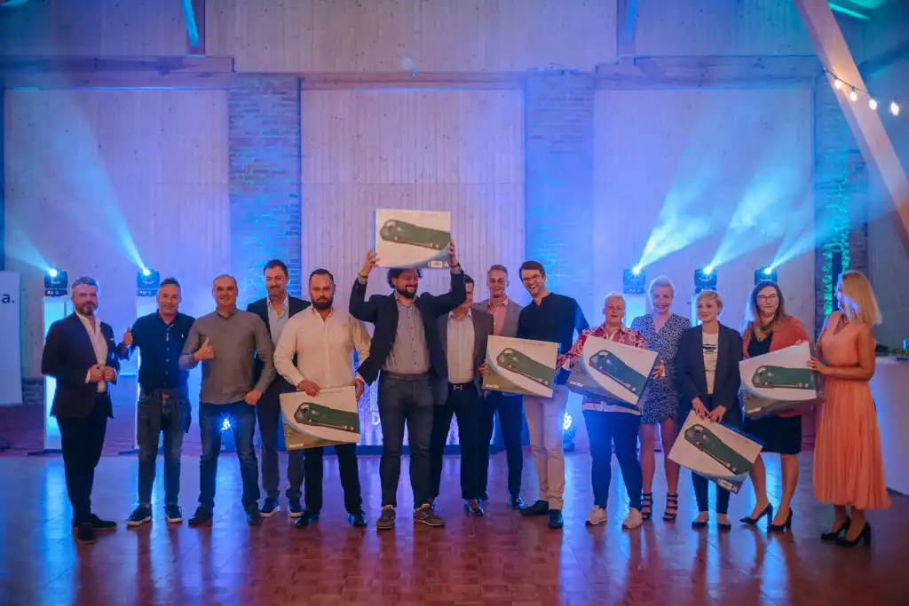 Uczestnicy stoją na scenie podczas wieczornej gali wręczenia dyplomów, podsumowującej firmowy event golfowy.