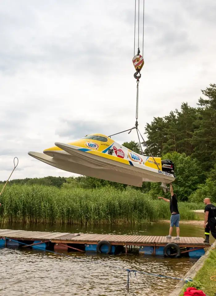 Event z serii Piąty Żywioł Woda, przedstawiający łódź wyścigową opuszczaną do wody przy pomocy dźwigu.
