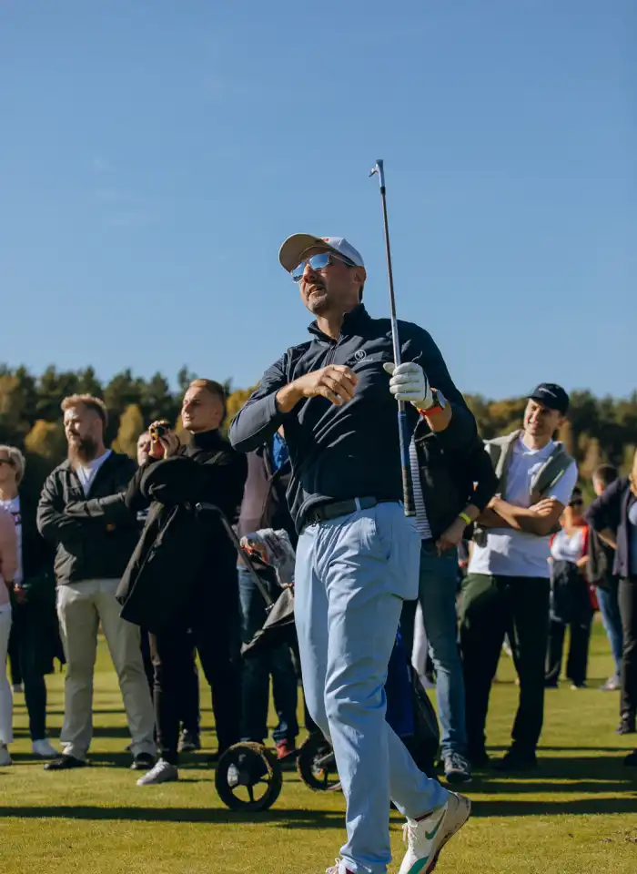 Jerzy Dudek wykonuje udany zamach kijem golfowym, prezentując technikę uderzenia uczestnikom sportowego eventu.