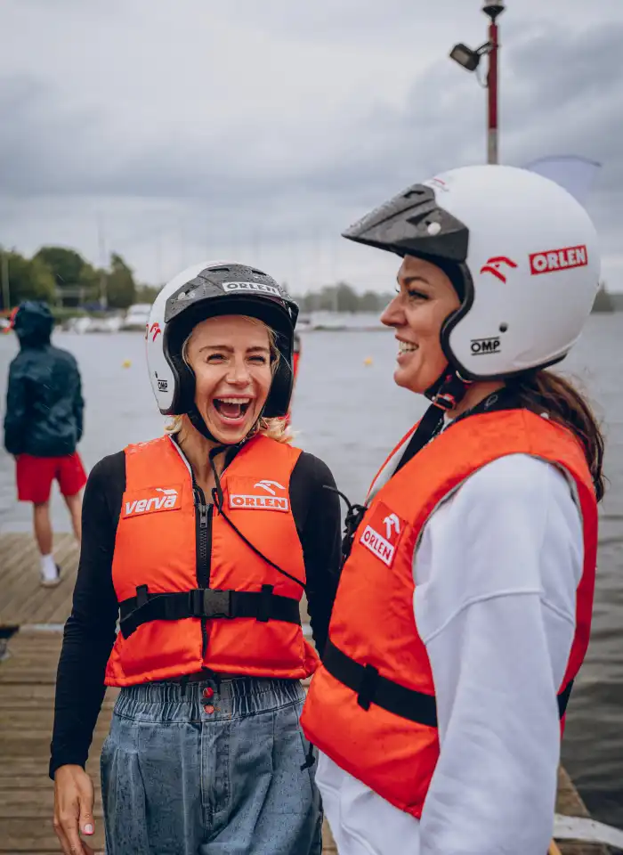 Uśmiechnięte uczestniczki eventu w kaskach i kamizelkach asekuracyjnych pozują w strefie przygotowań przed częścią wodną.