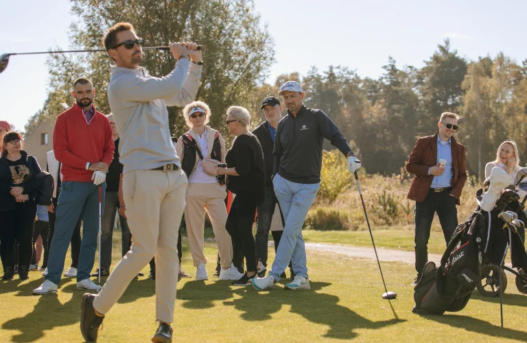 Uczestnik wykonuje mocny zamach kijem, uderzając piłkę na polu golfowym podczas aktywnej części wydarzenia.
