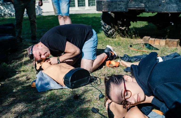 Grupa uczestników podczas szkolenia z pierwszej pomocy na manekinach.