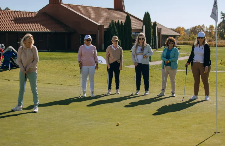 Zawodniczka uderza piłkę w kierunku dołka z bliskiej odległości, skupiając się na precyzji na greenie.