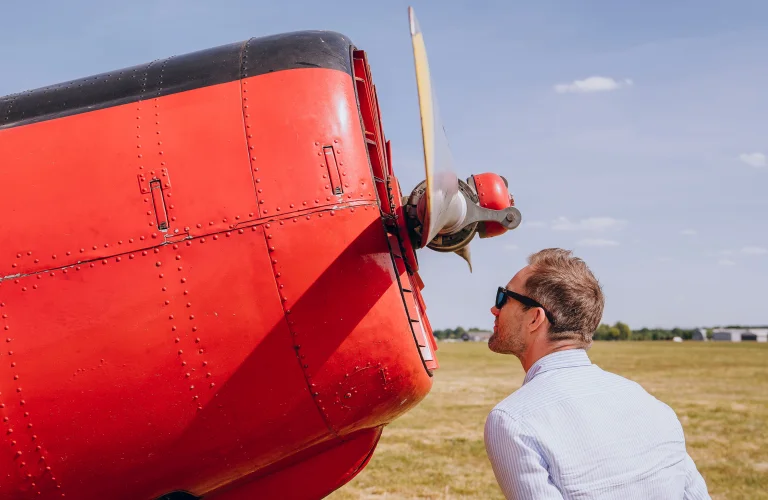 Uczestnik stoi przy śmigle samolotu podczas części prezentacyjnej wydarzenia lotniczego.