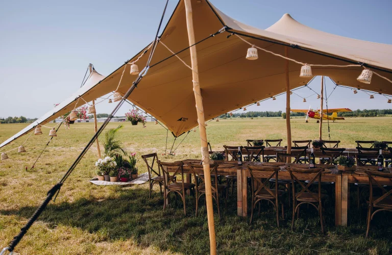 Namiot eventowy ustawiony na lotnisku, pełniący funkcję strefy spotkań i odprawy uczestników wydarzenia.
