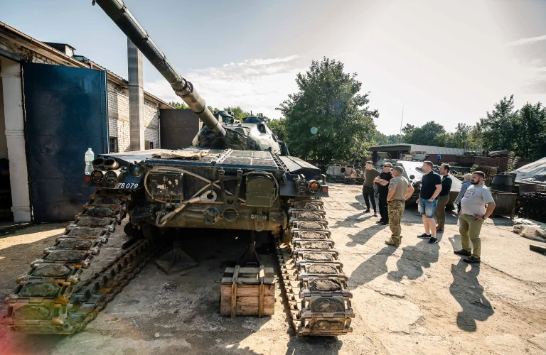 Grupa uczestników przygląda się czołgowi rozłożonemu na części.
