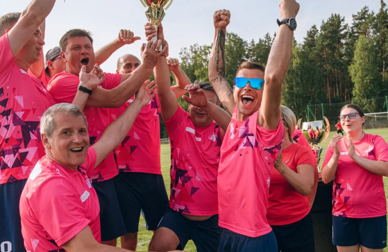 Event z serii Piąty Żywioł Ziemia, na którym drużyna w różowych koszulkach prezentuje puchar zdobyty w rywalizacji firmowej.