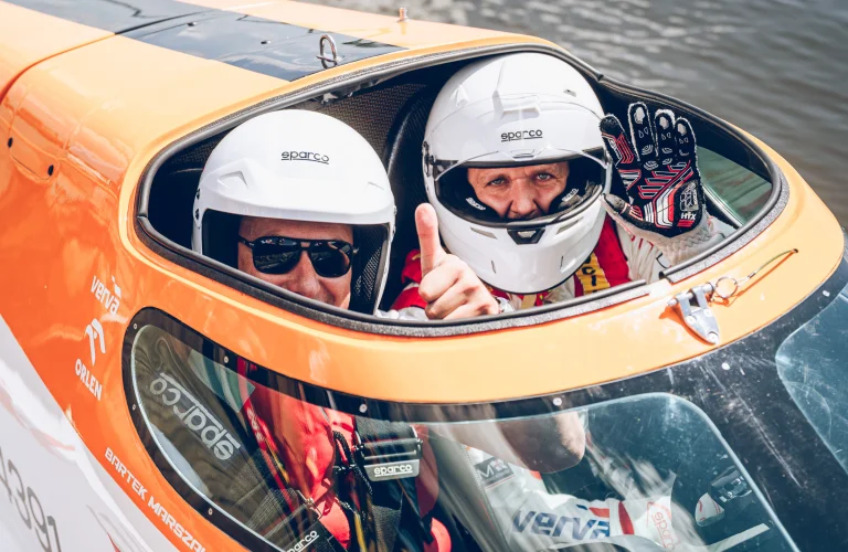 Event z serii Piąty Żywioł Woda z Bartkiem Marszałkiem i uczestnikiem siedzącymi w łodzi F1H2O gotowej do przejazdu.