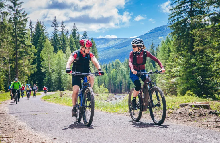 Uczestnicy jadą na rowerach przez górską łąkę, przemieszczając się wzdłuż malowniczej, otwartej przestrzeni.