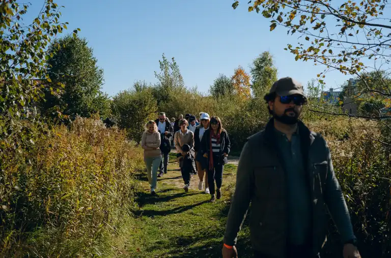 Grupa uczestników spaceruje po polu golfowym, przemieszczając się pomiędzy kolejnymi stanowiskami gry.