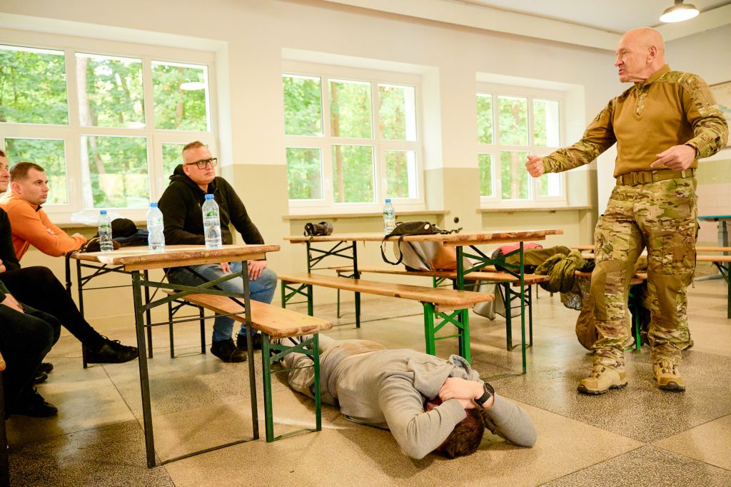 Ćwiczenie reagowania na napastnika w biurze, jedna z osób leży na podłodze sali